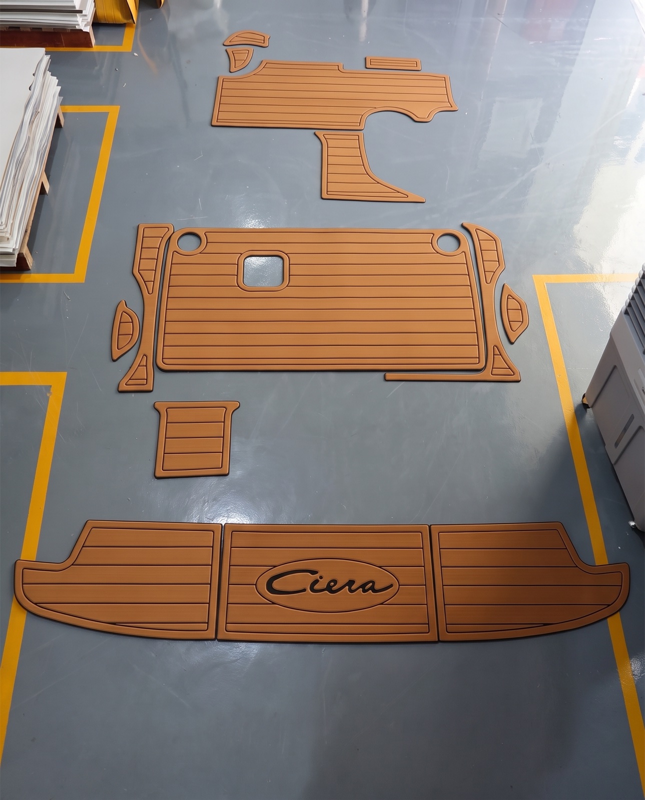 A milled set of teak-pattern foam panels laid out on the shop floor, boat name routed into the transom piece